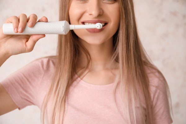 Girl brushing her teeth with an Electric toothbrush 